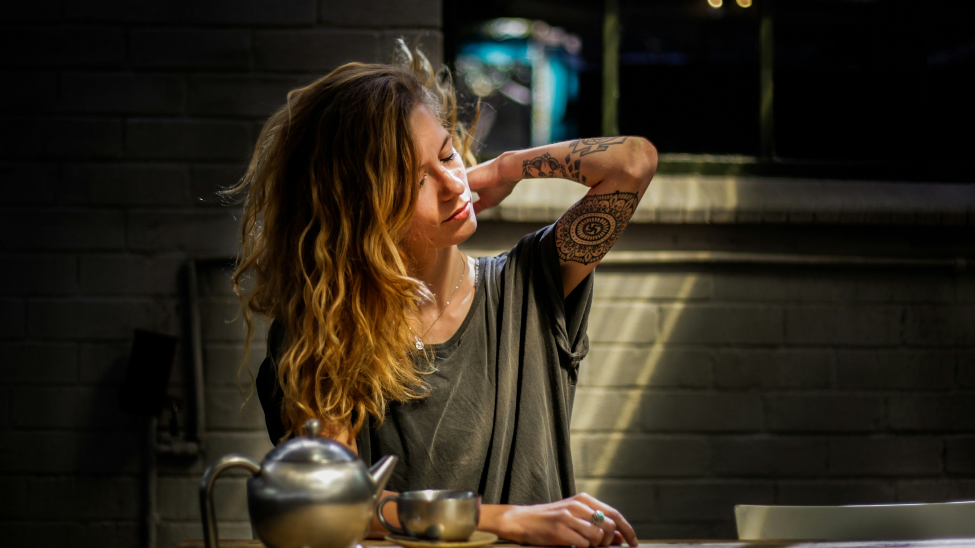 Woman with tattoos making tea and looking stressed. 